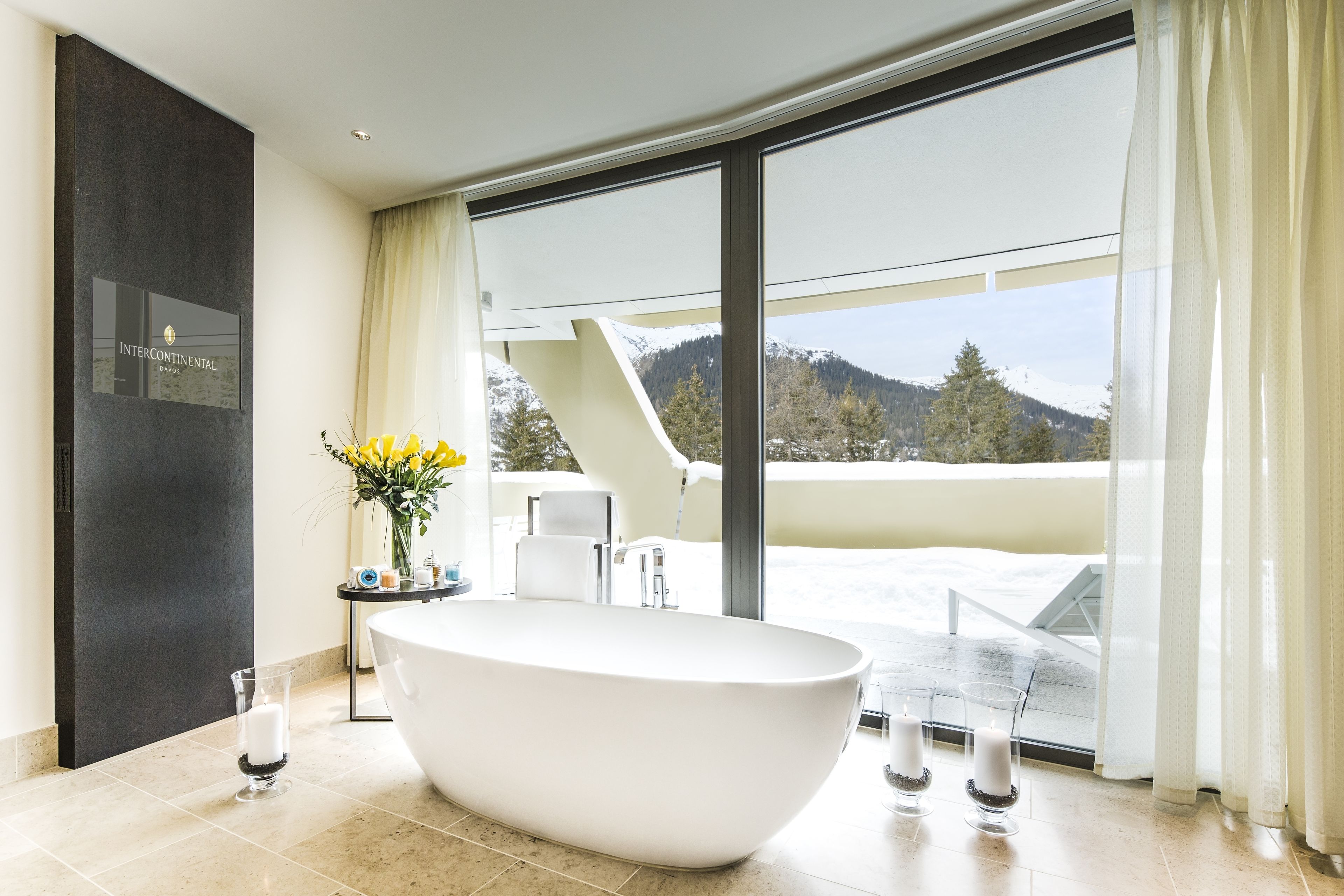 A modern bathroom with a freestanding bathtub, a large window with a mountain view, and a minimalist decor.