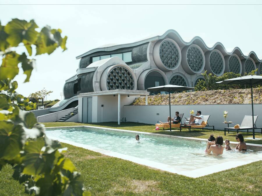 A modern pool area with a unique architectural design, including a curved structure and circular windows.