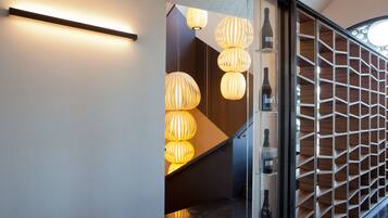 Un interior moderno con una escalera, iluminado por lámparas colgantes esféricas y un panel de pared de madera.