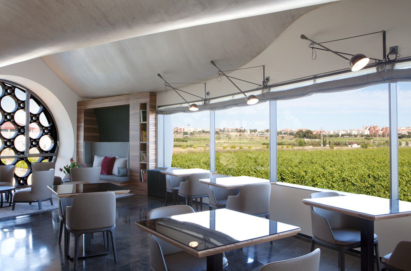 Un interior moderno con zona de estar, ventanas amplias y vistas al campo.