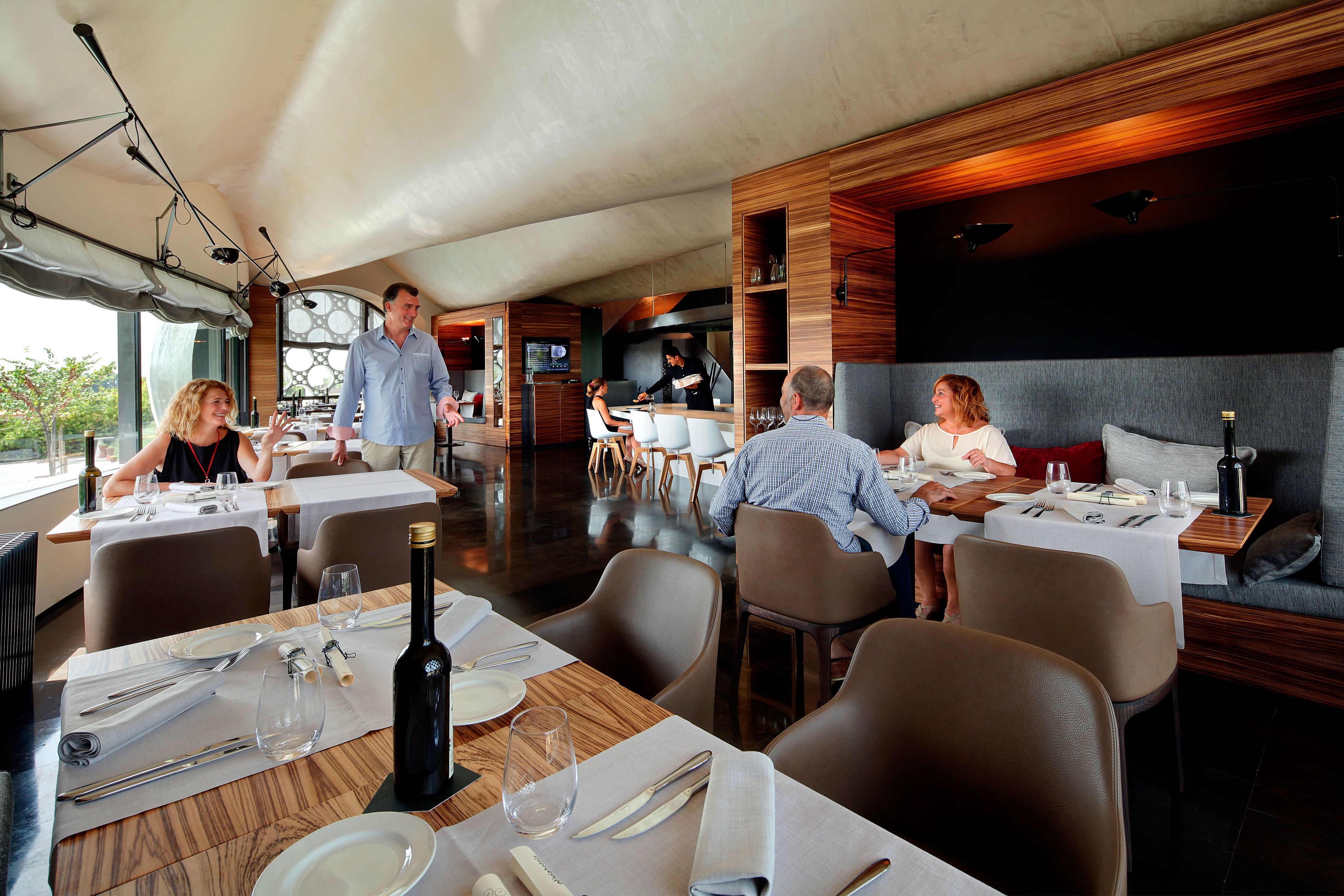Un restaurante moderno con mesas listas para comer, una zona de bar y vistas al exterior.