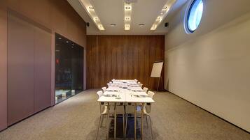 A conference room with a long table, chairs, a projector, and a whiteboard.