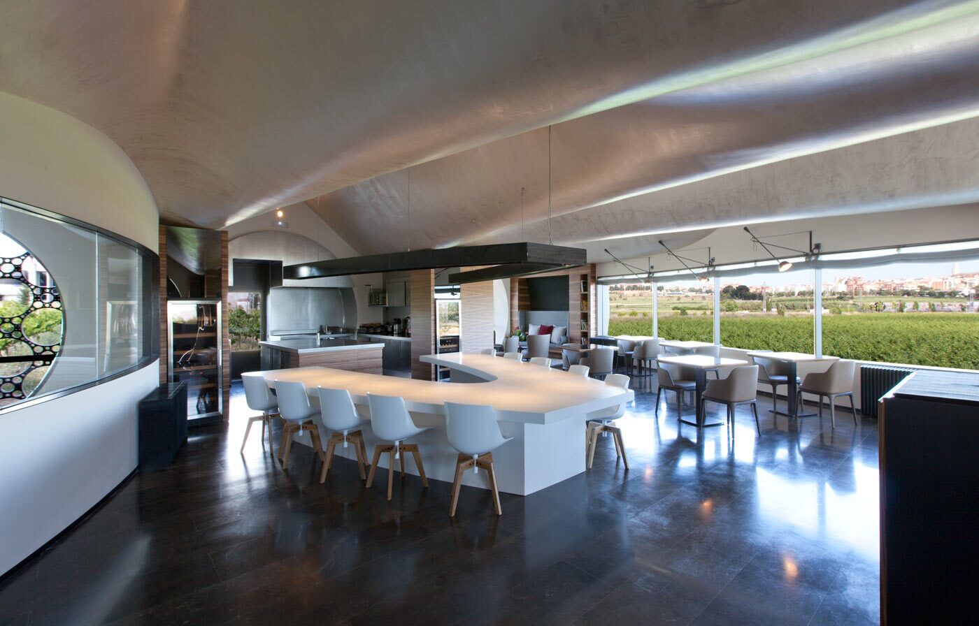 Una cocina moderna con una isla grande, taburetes de bar y vistas al exterior.