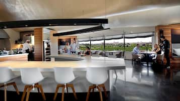 A modern kitchen with a central island, white bar stools, and a view of the city.