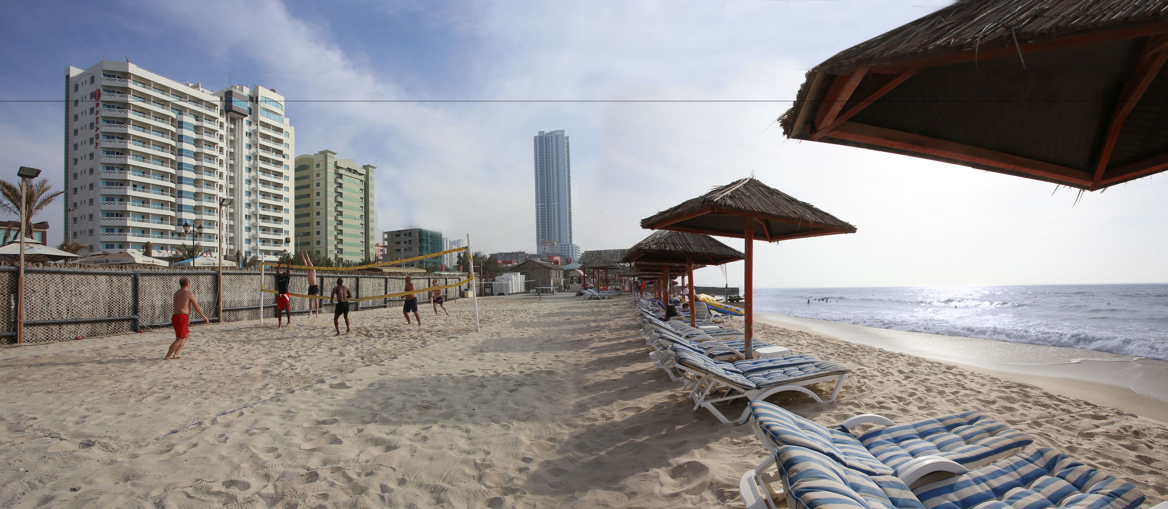 A beach with sun loungers and a volleyball net.