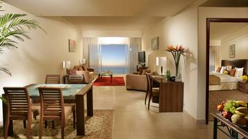 Ein Hotelzimmer mit Essbereich, einem Wohnzimmer mit Blick sowie einem Fernseher und einer Obstschale.