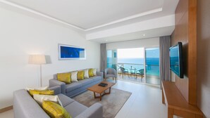 Un salon moderne avec un canapé, une table basse et un téléviseur. Il y a un balcon avec vue sur l’océan.