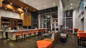 Un espace bar moderne avec un plafond en bois, un comptoir et des sièges orange.