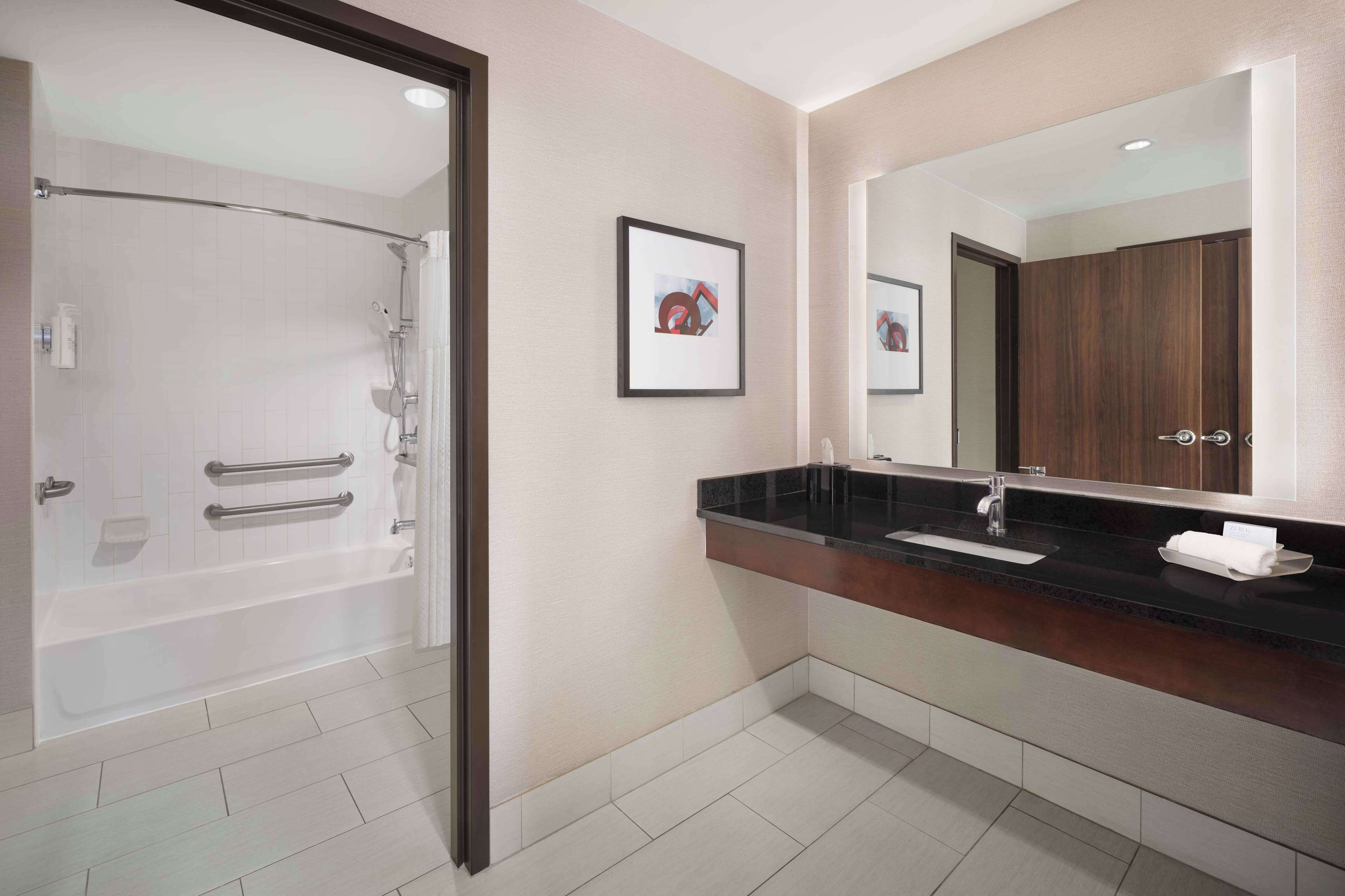A modern bathroom with a bathtub, a vanity with a sink, and a large mirror.