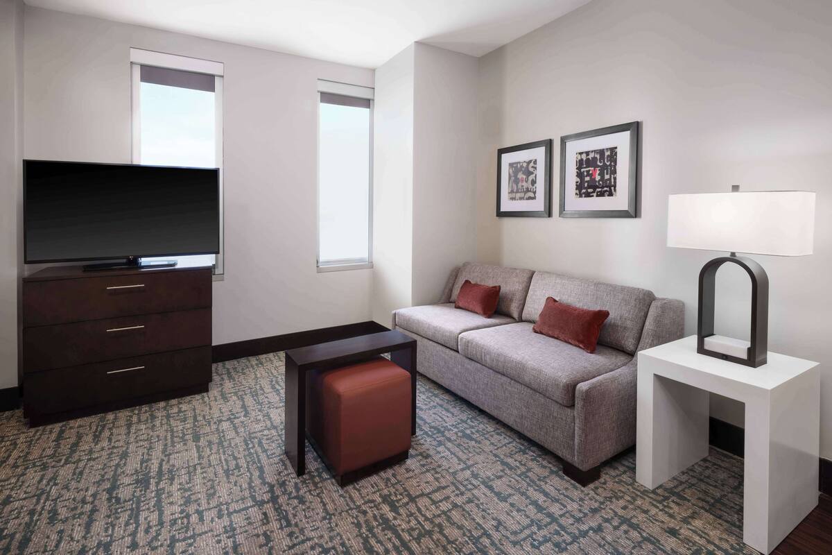 Een moderne hotelkamer met een flatscreen televisie, een bank, een klein tafeltje en een lamp.