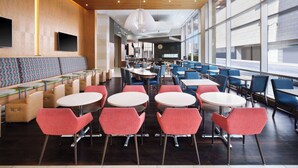 Un espace repas moderne avec des tables et des chaises rondes, un long banc et une grande fenêtre qui laisse entrer la lumière naturelle.