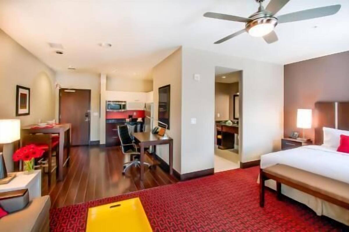 Een hotelkamer met een bed, bureau, stoel en een kitchenette.