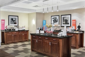 A hotel kitchen with wooden cabinets, granite countertops, and various kitchen appliances.