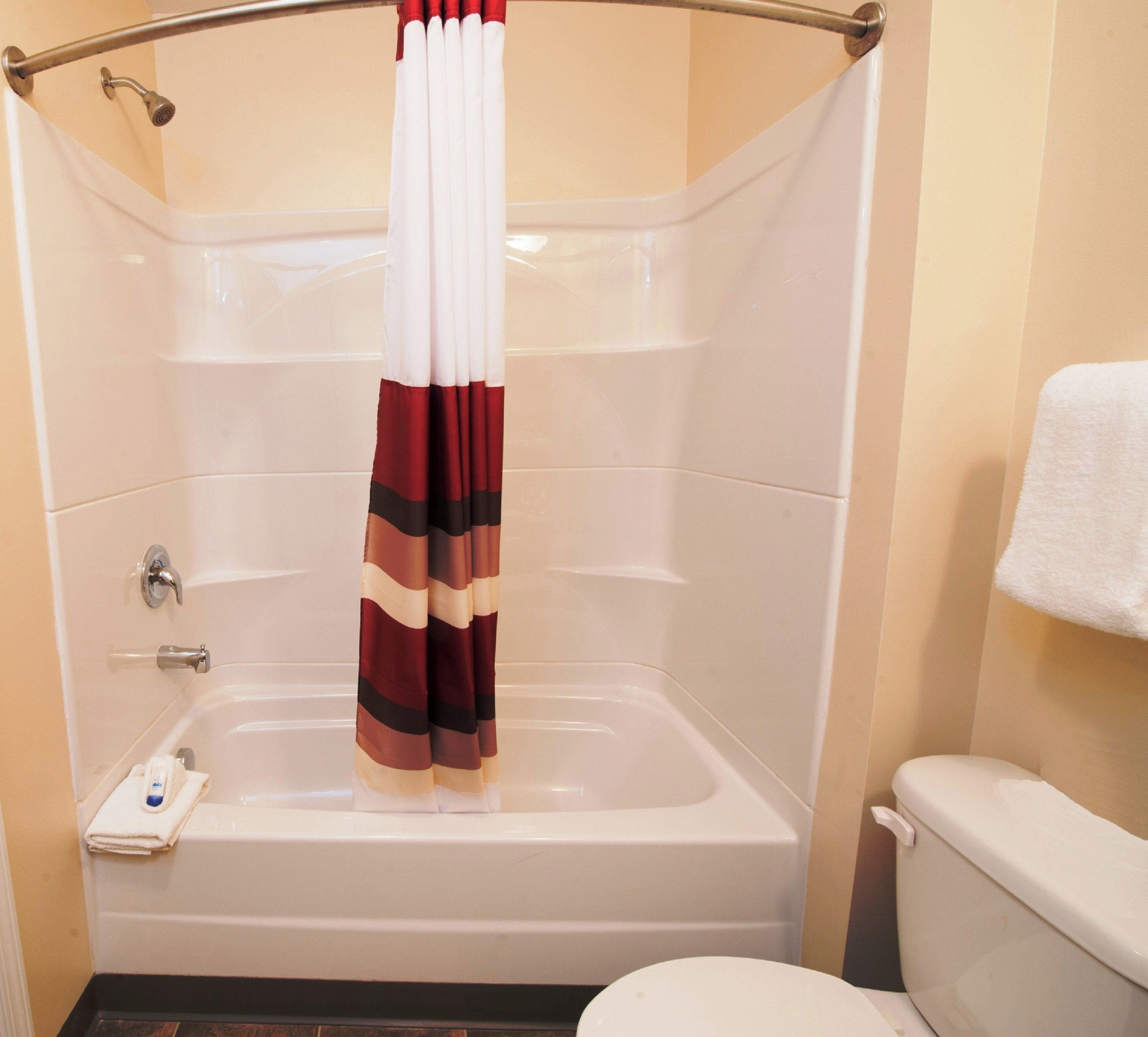 A bathroom with a bathtub, a shower curtain, and a toilet.