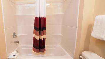 A bathroom with a bathtub, a shower curtain, and a toilet.
