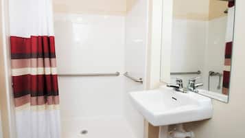 A bathroom with a shower, a white sink, and a mirror.