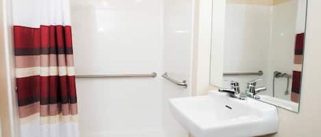 A bathroom with a shower, a white sink, and a mirror.