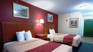 A hotel room with two beds, a nightstand, a lamp, and framed pictures on the walls. - Red Roof Inn & Suites Dickinson (Dickinson)
