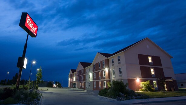A hotel with a red sign, multiple floors, and a parking lot. - Red Roof Inn & Suites Dickinson (Dickinson)