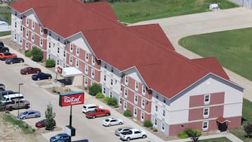A multi-story hotel with a red roof and a parking lot.