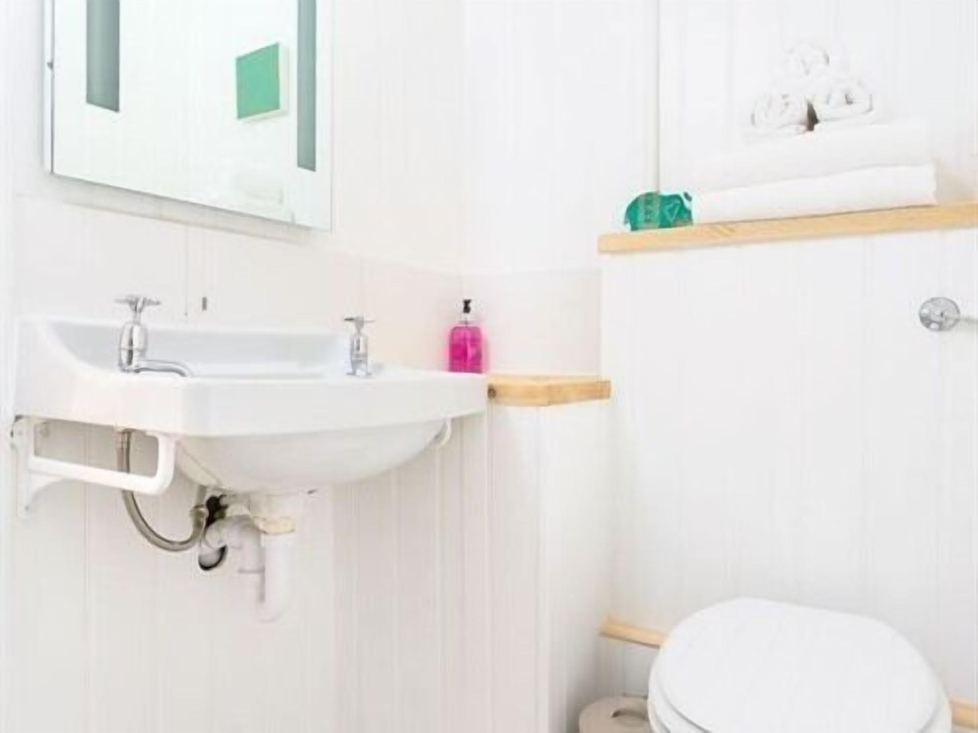 A bathroom with a white sink, a mirror, a toilet, and a towel rack.