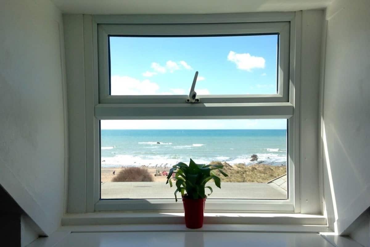 A window with a view of the beach and ocean.