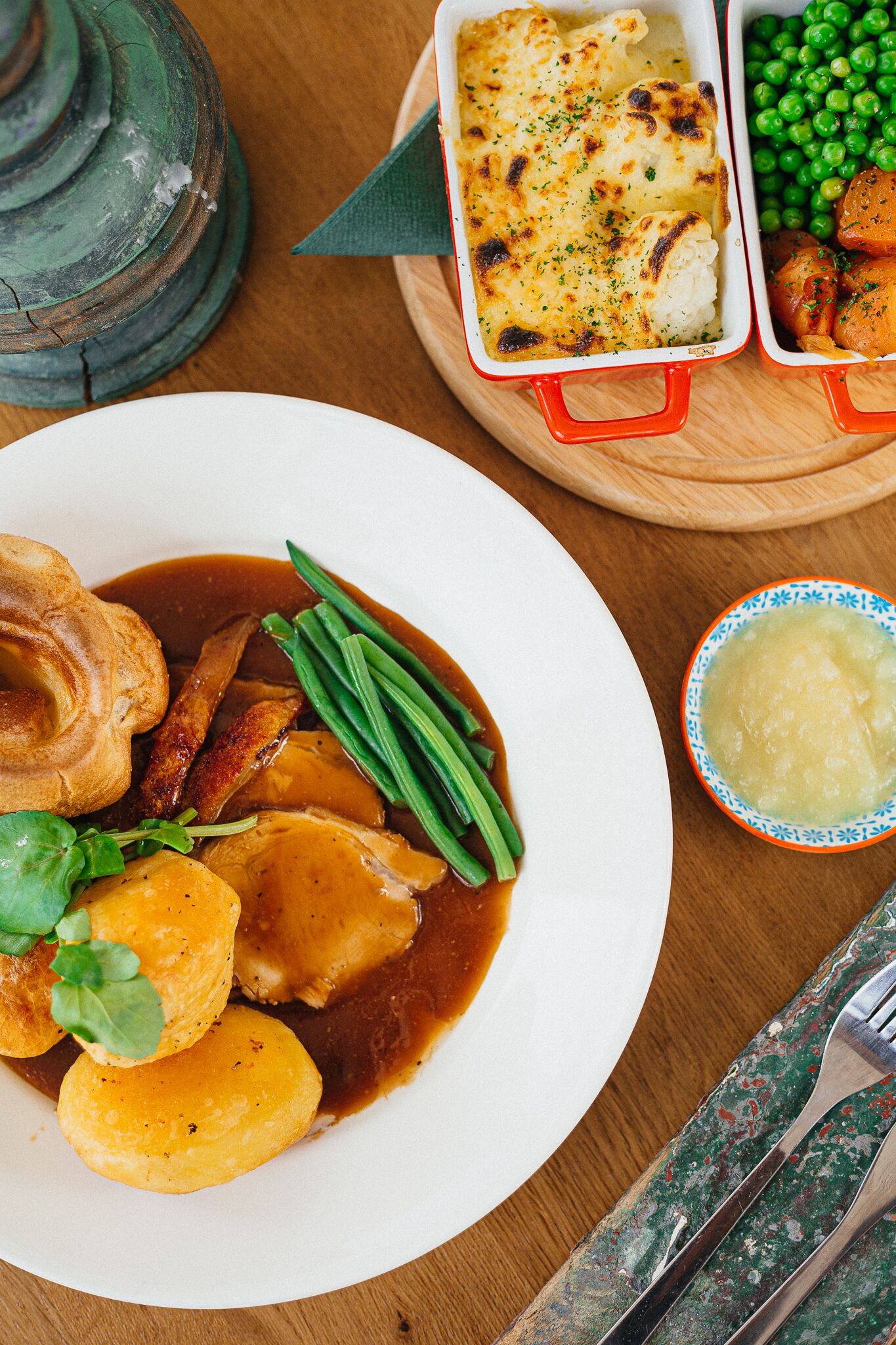 Een bord met rundvleesgebraad, Yorkshire pudding, groene bonen en jus.