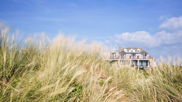 A beach house hotel with a large, two-story structure, multiple windows, and a prominent entrance.