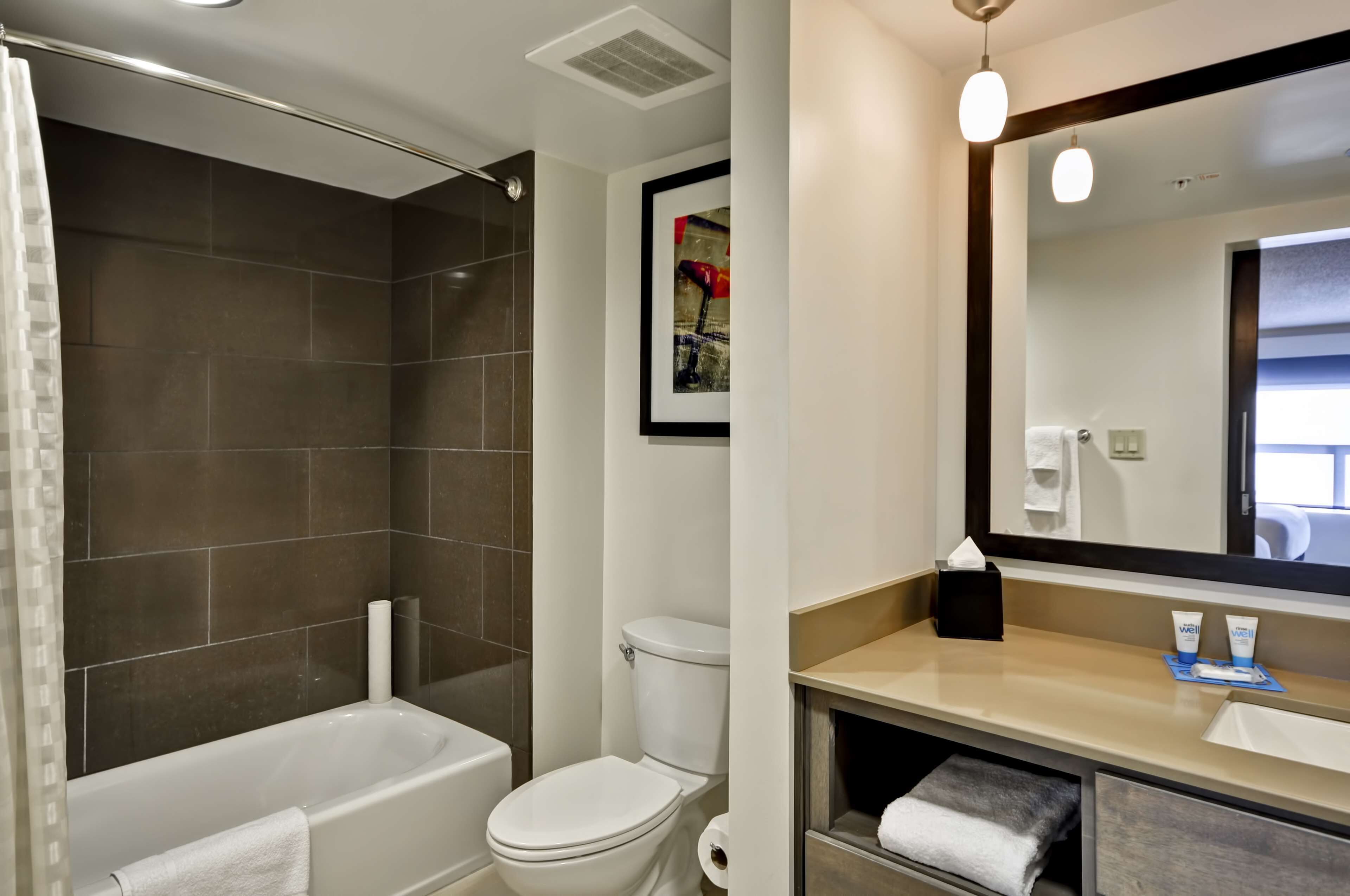 Ein Badezimmer mit Badewanne, Toilette und Waschtisch mit Spiegel.