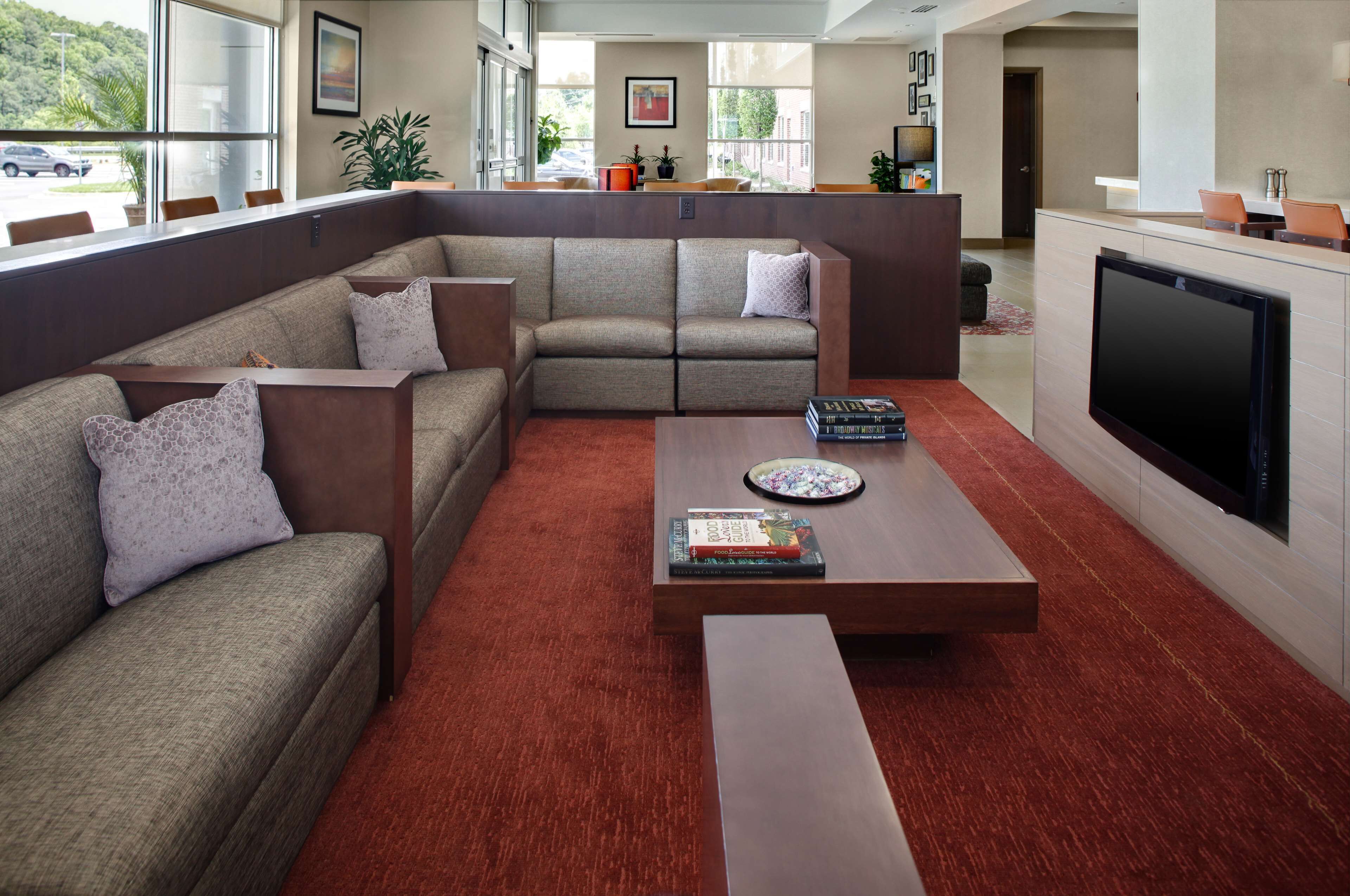 A modern living room with a sectional sofa, a flat-screen TV, and a coffee table with books.