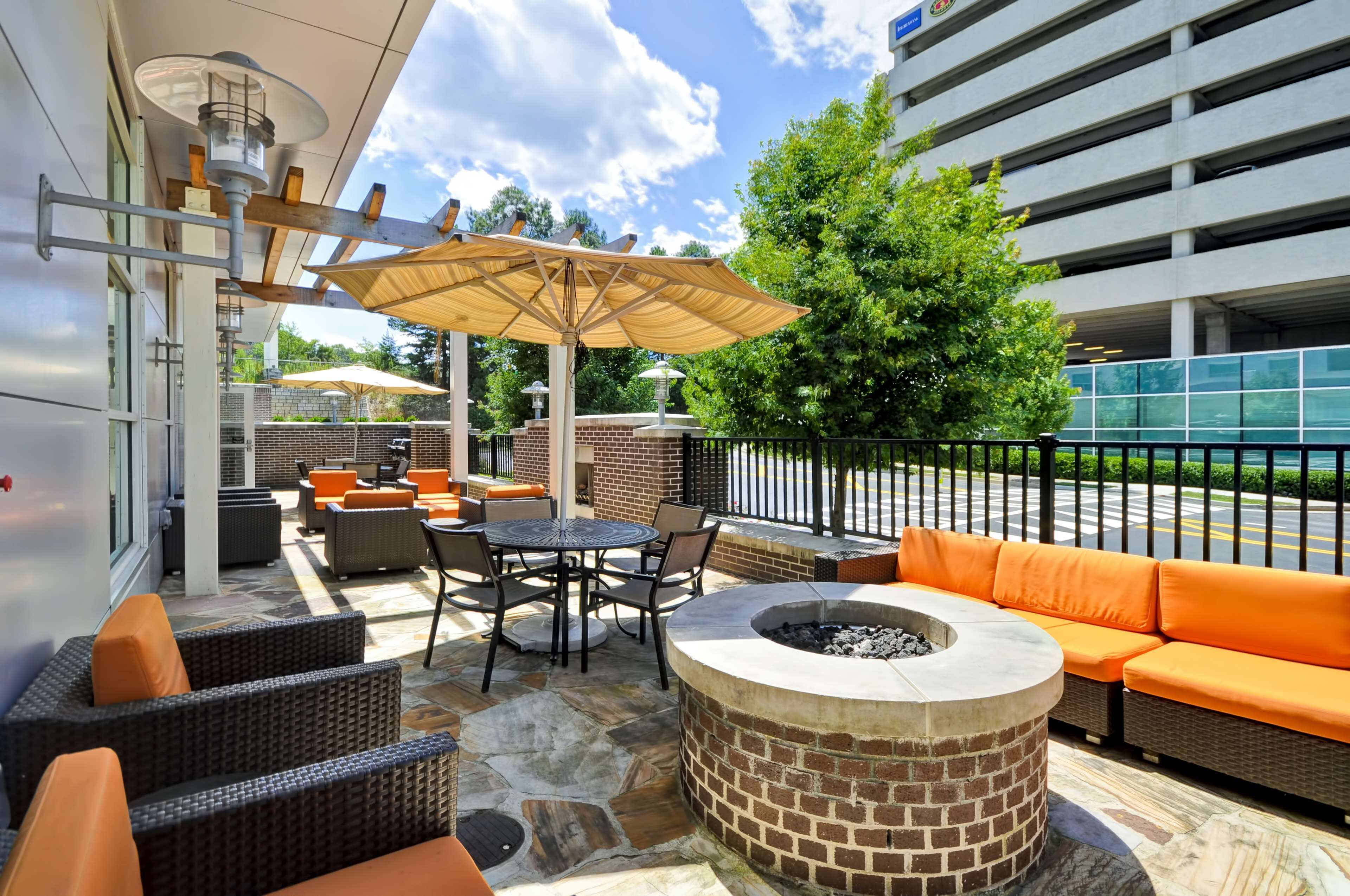 An outdoor patio area with a fire pit, seating, and umbrellas.