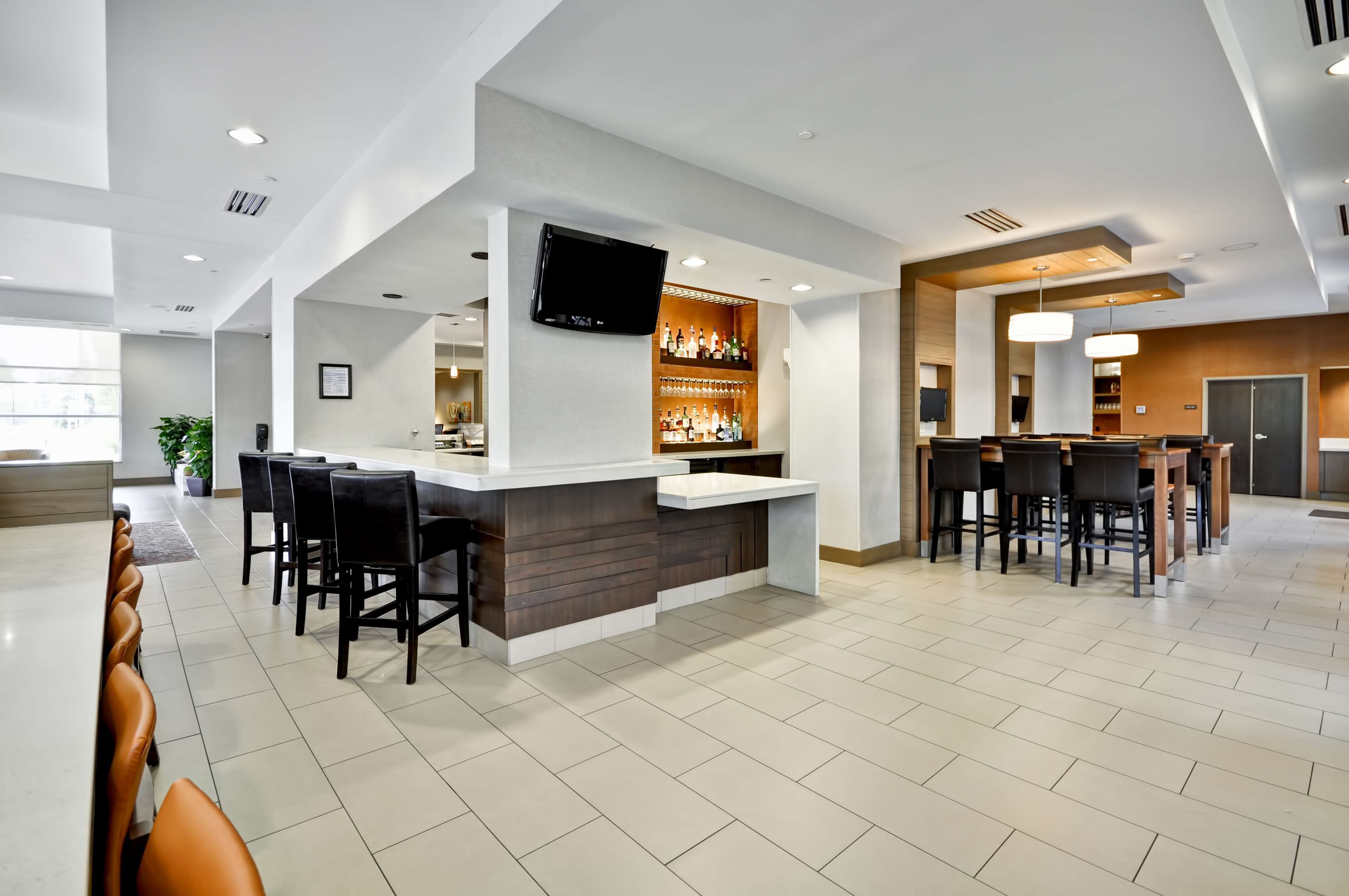 A modern bar area with a flat-screen TV, a bar counter, and seating.