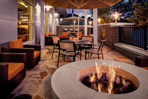 Un patio exterior con una chimenea, mobiliario de mimbre y paredes de ladrillo.