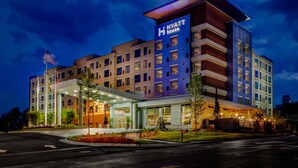 Un hôtel à plusieurs étages, reconnaissable à son grand panneau « Hyatt House », qui présente une architecture moderne avec un toit plat et de grandes fenêtres.