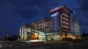 A multi-story hotel with a prominent 'Hyatt House' sign, a covered entrance, and a landscaped front yard.