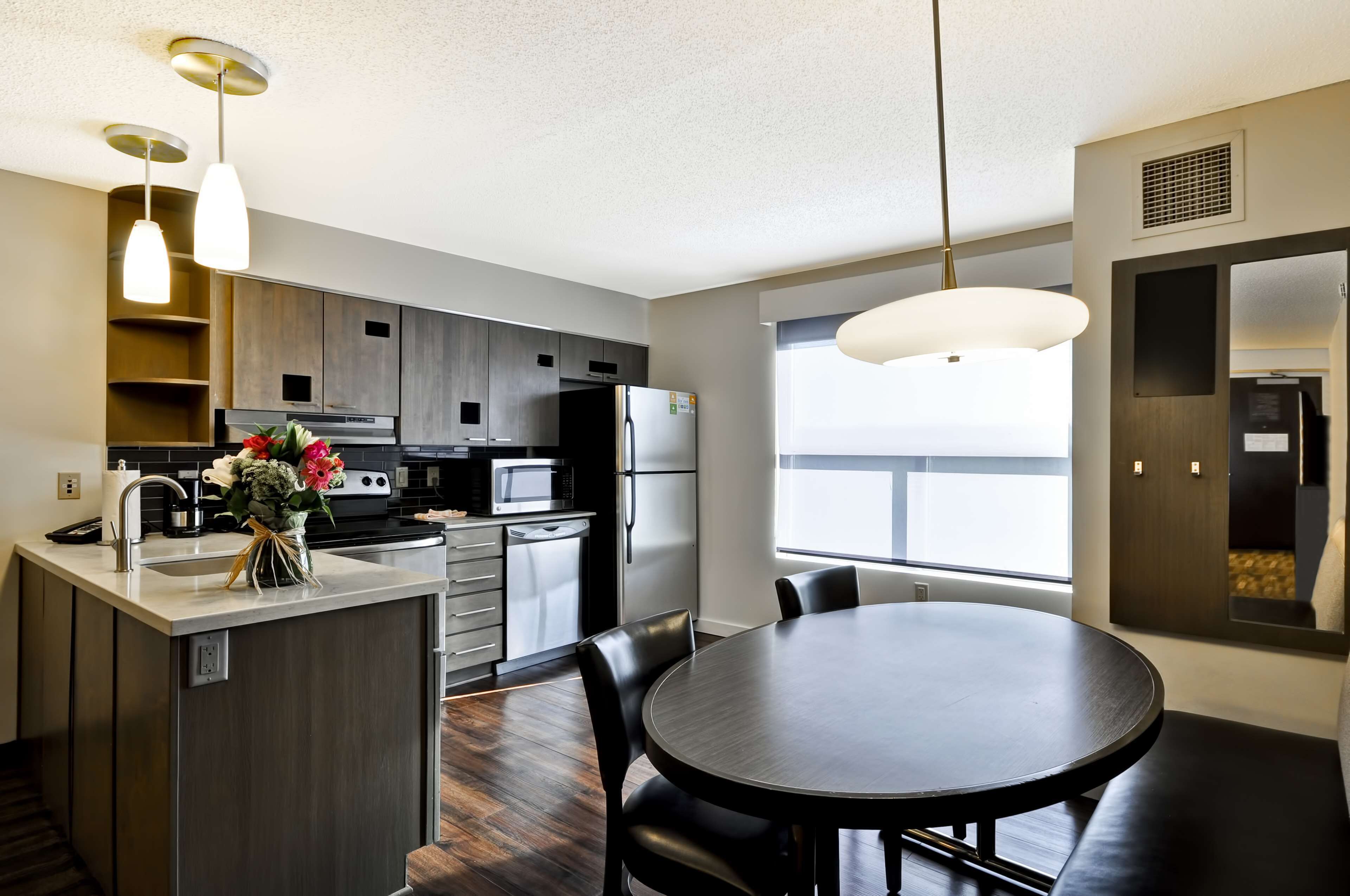 A modern kitchen with a central island, stainless steel appliances, and a dining area with a round table and chairs.