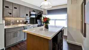 Une cuisine moderne avec des meubles de couleur grise, un îlot central et un luminaire suspendu.