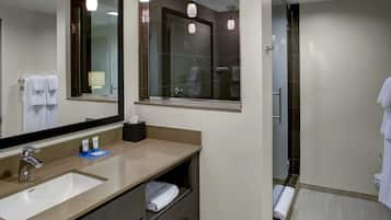 Un baño moderno con un espejo grande, un lavabo y una zona de ducha.