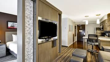 Una habitación de hotel moderna con una cama, un televisor, un escritorio con una silla y una kitchenette.