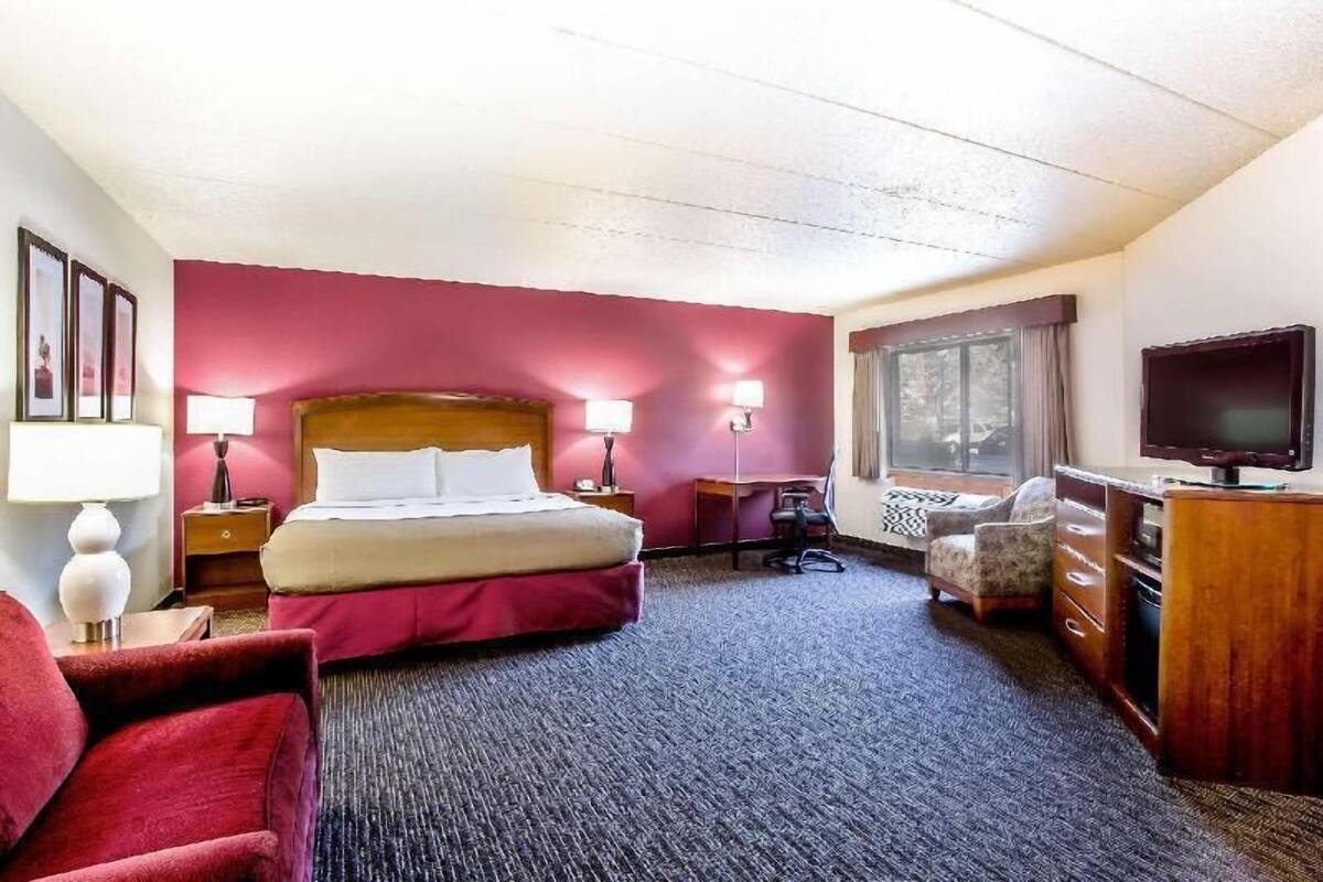 Una habitación de hotel con una cama, un escritorio, una silla, un televisor y una ventana.