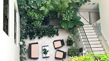 Un pati amb una escala, plantes en testos i mobiliari per a l'exterior.
