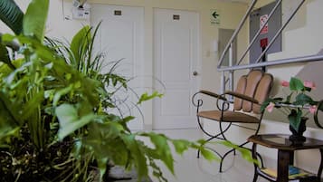 A waiting area with a chair, a table with a vase of flowers, and a staircase.