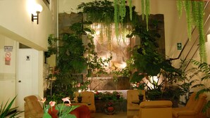 A lobby with a stone wall, hanging plants, and yellow chairs. - Casa Fanning Apart Hotel (Lima)