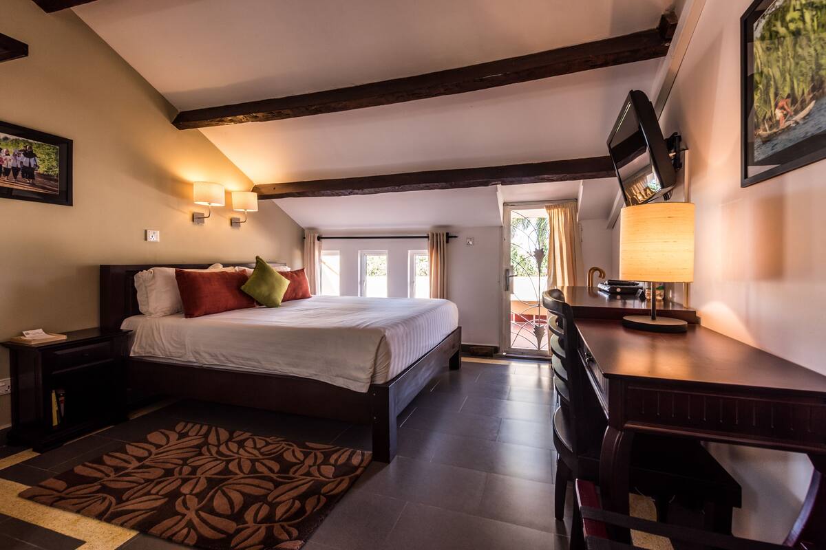 A bedroom with a bed, bedside table, lamp, and a desk with a chair.