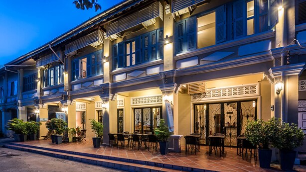 A traditional building with multiple balconies, outdoor seating, and potted plants. - The Columns (Kampot)