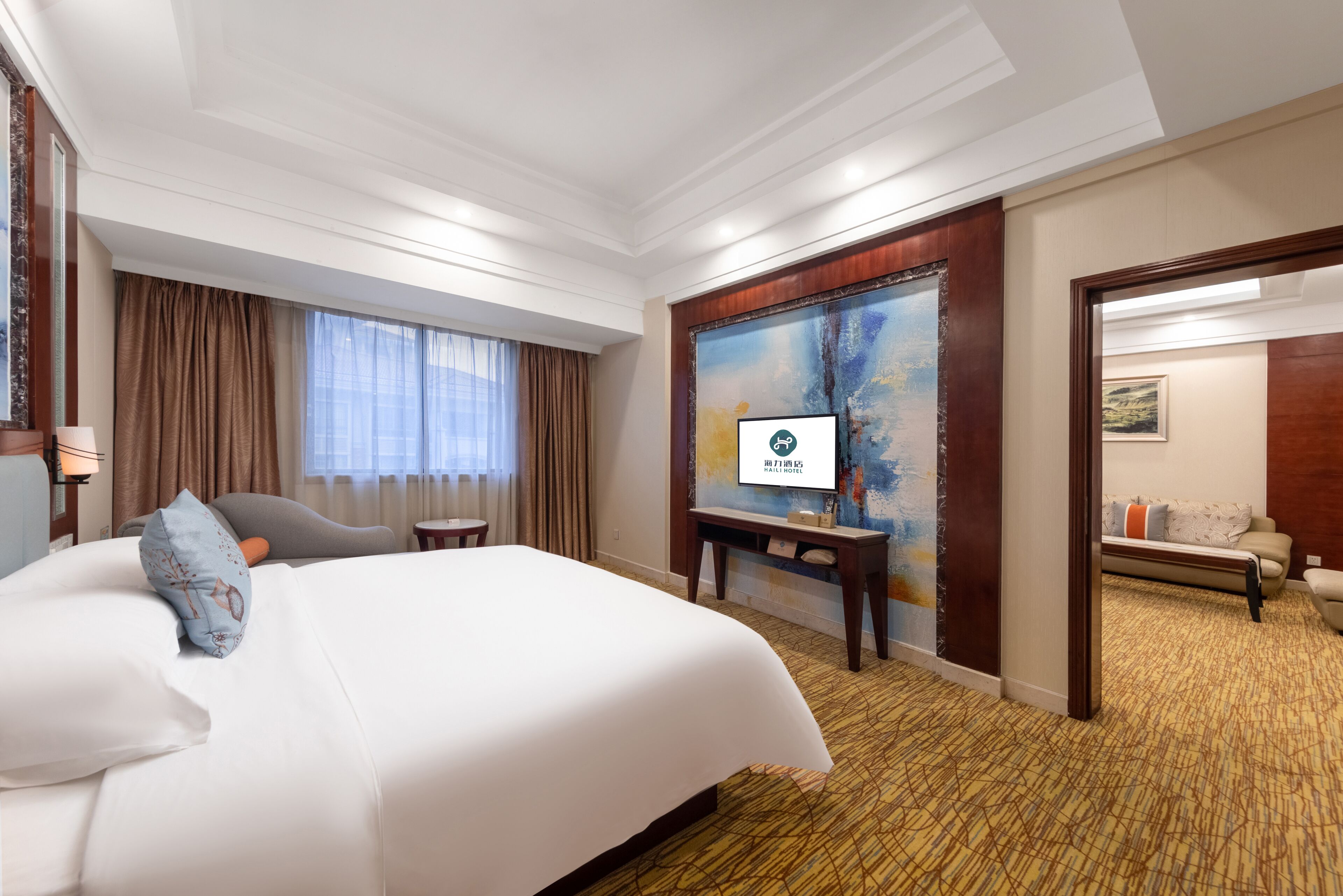 Habitación de hotel con una cama grande, un escritorio, televisión y vistas al exterior por la ventana.