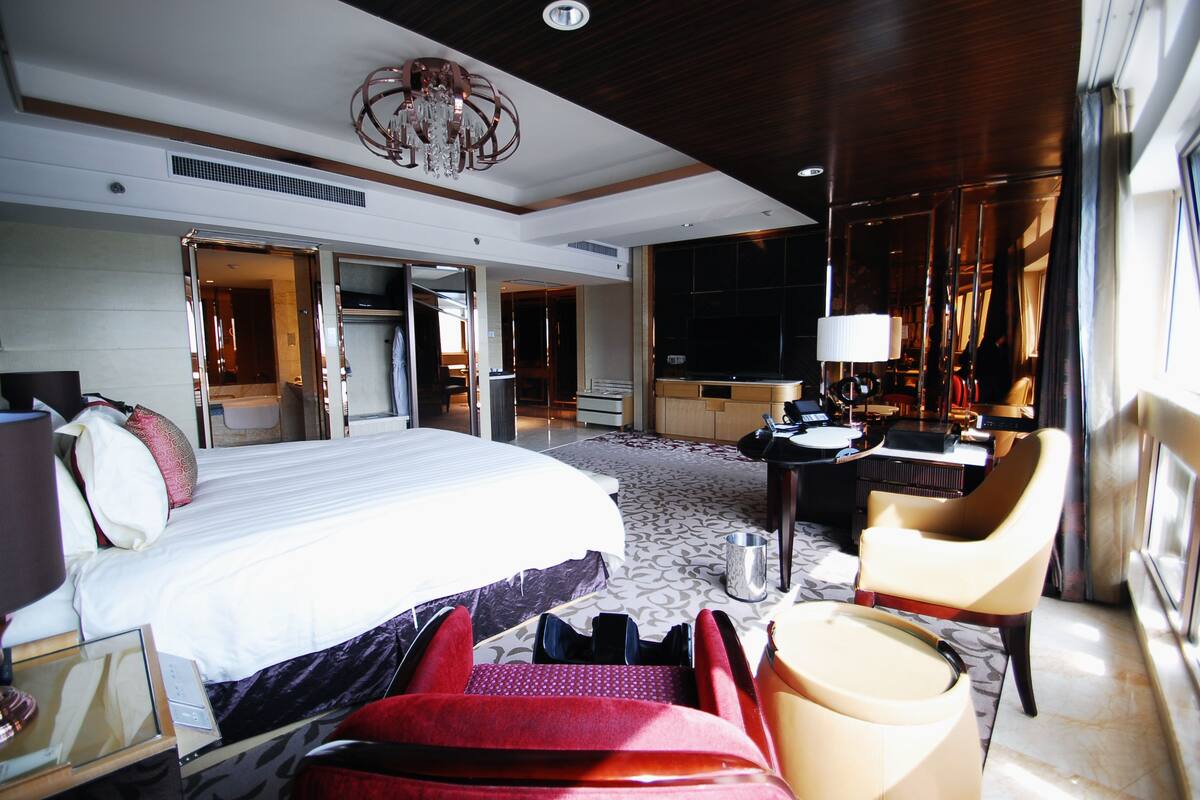 Ein geräumiges Hotelzimmer mit einem großen Bett, einem Schreibtisch, einem Sessel und einem kleinen Tisch.