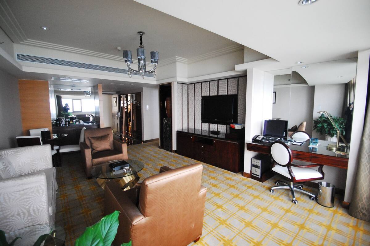 Ein Hotelzimmer mit Wohnbereich, Essbereich, Arbeitsplatz und Fernseher.