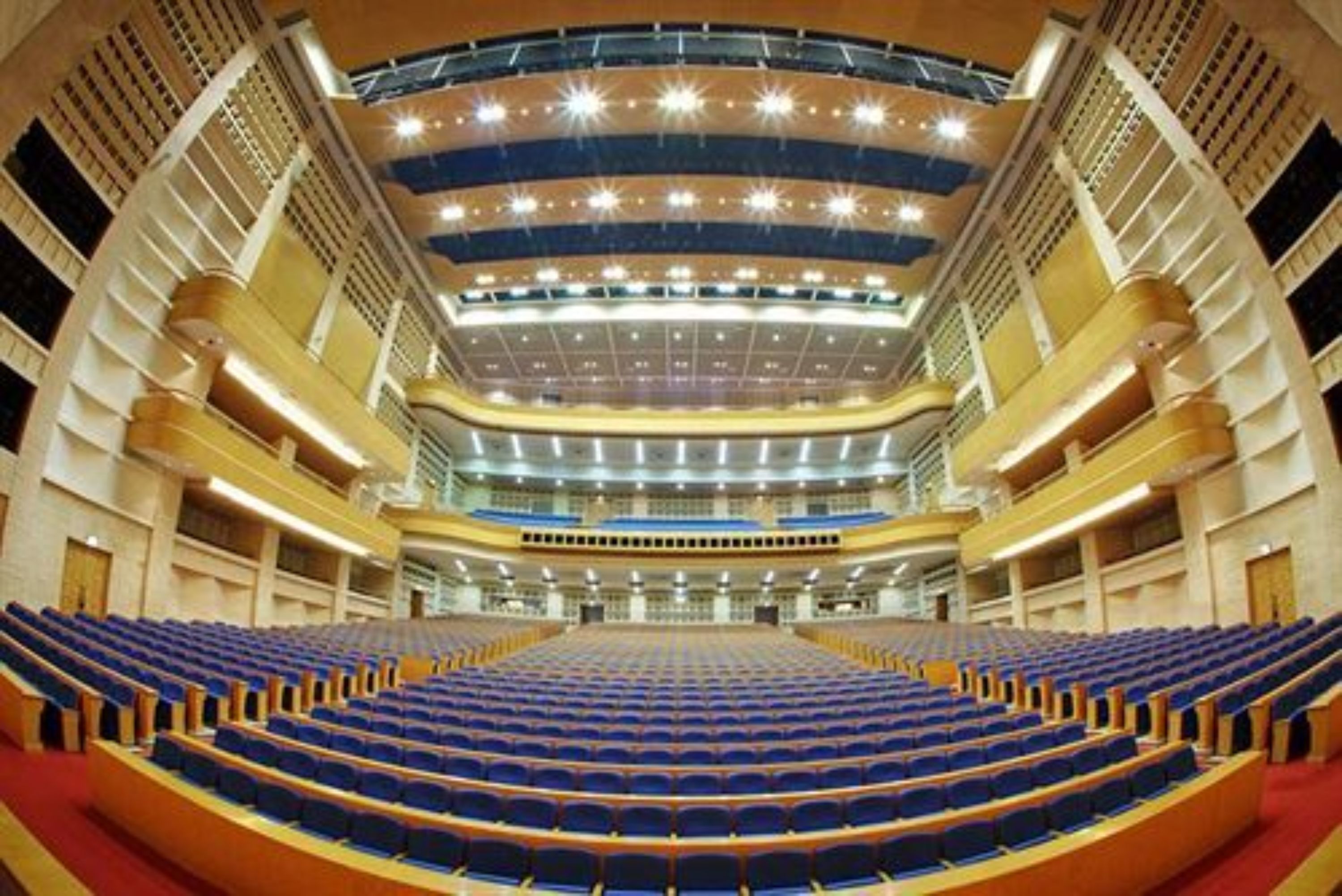 A large, modern auditorium with tiered seating and a central stage.