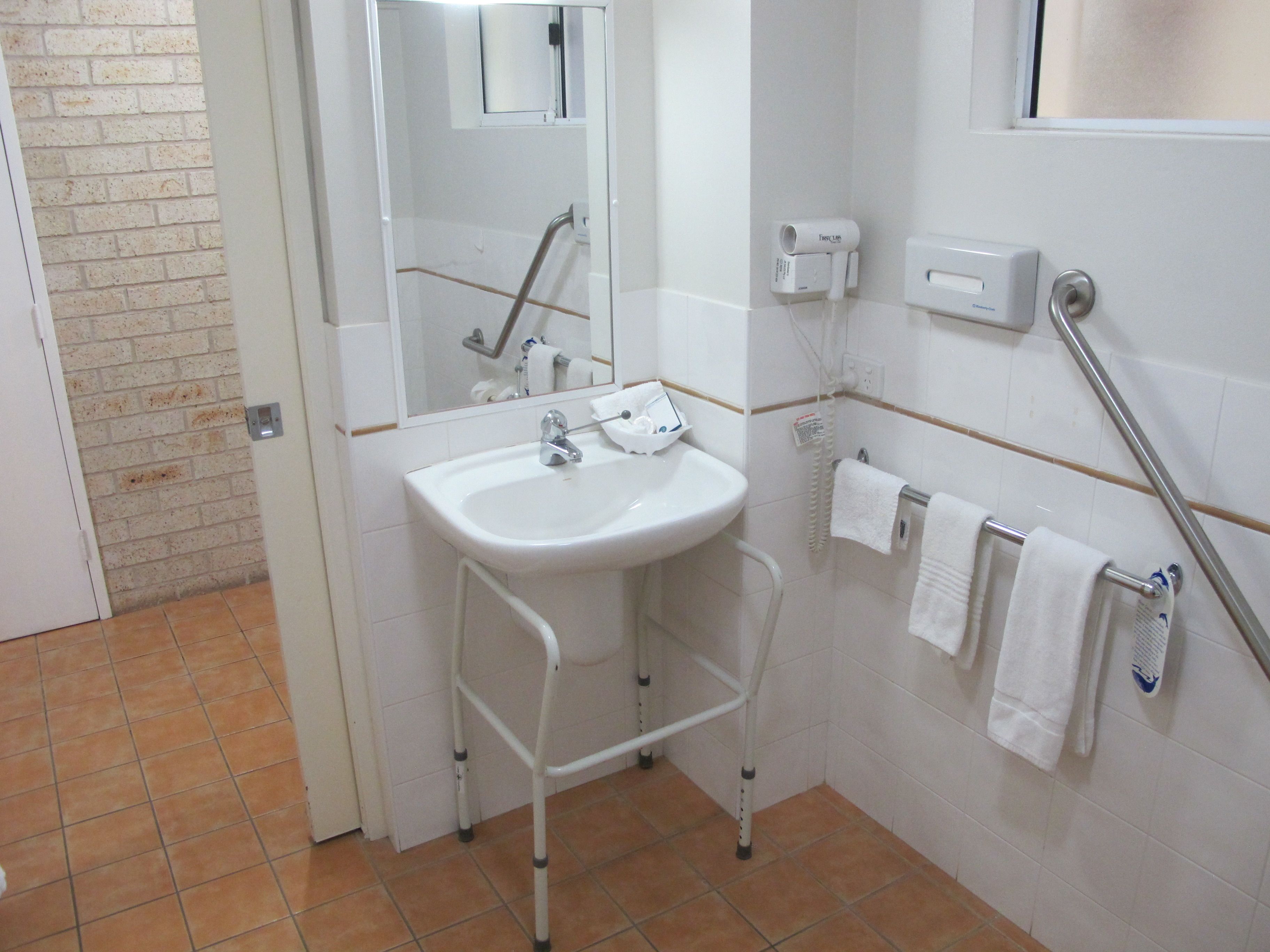 A bathroom with a white sink, a mirror, a towel rack, and a hand dryer.